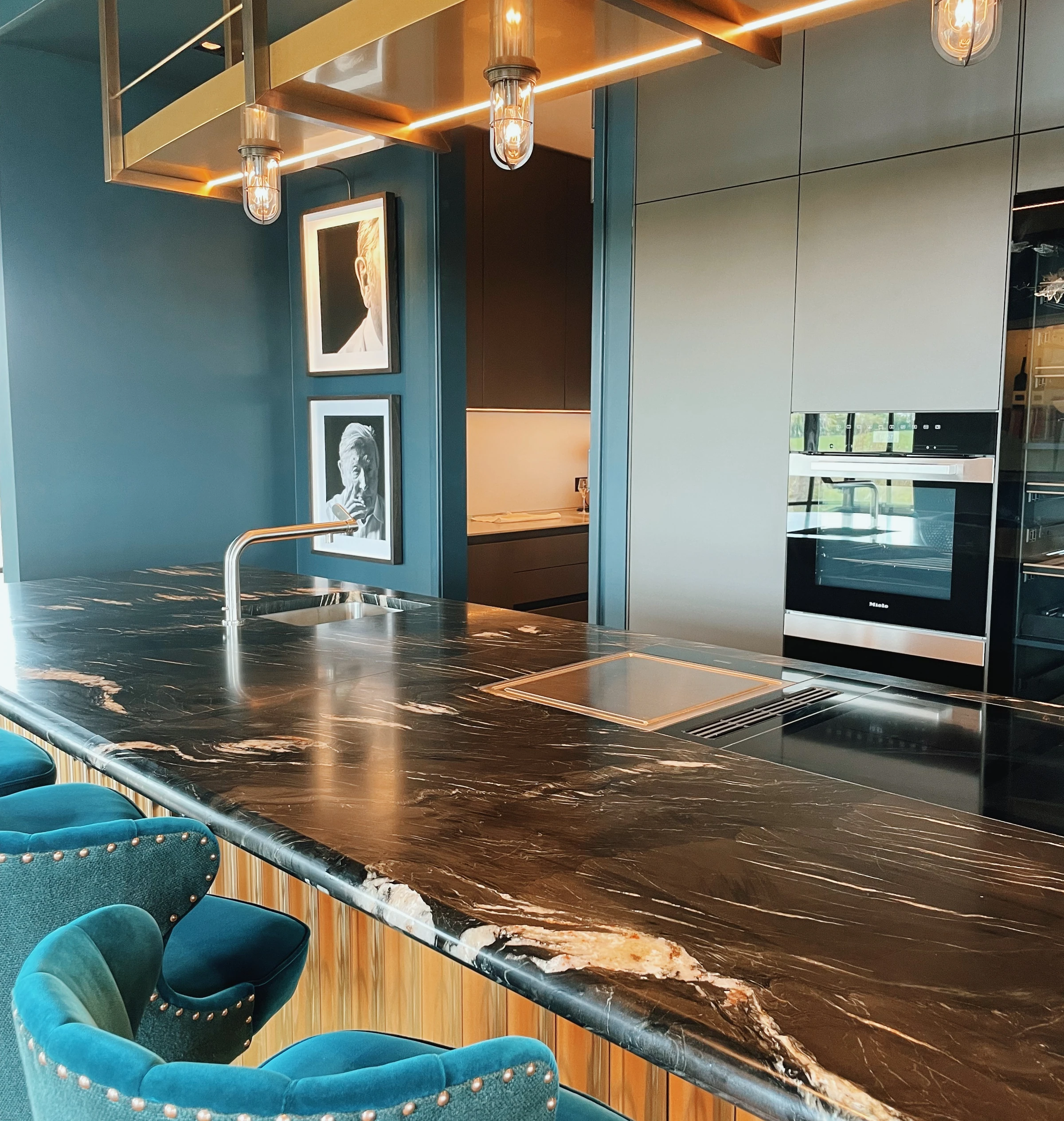 Modern kitchen and tasting area at Exton Park, with a marble island and teal velvet chairs