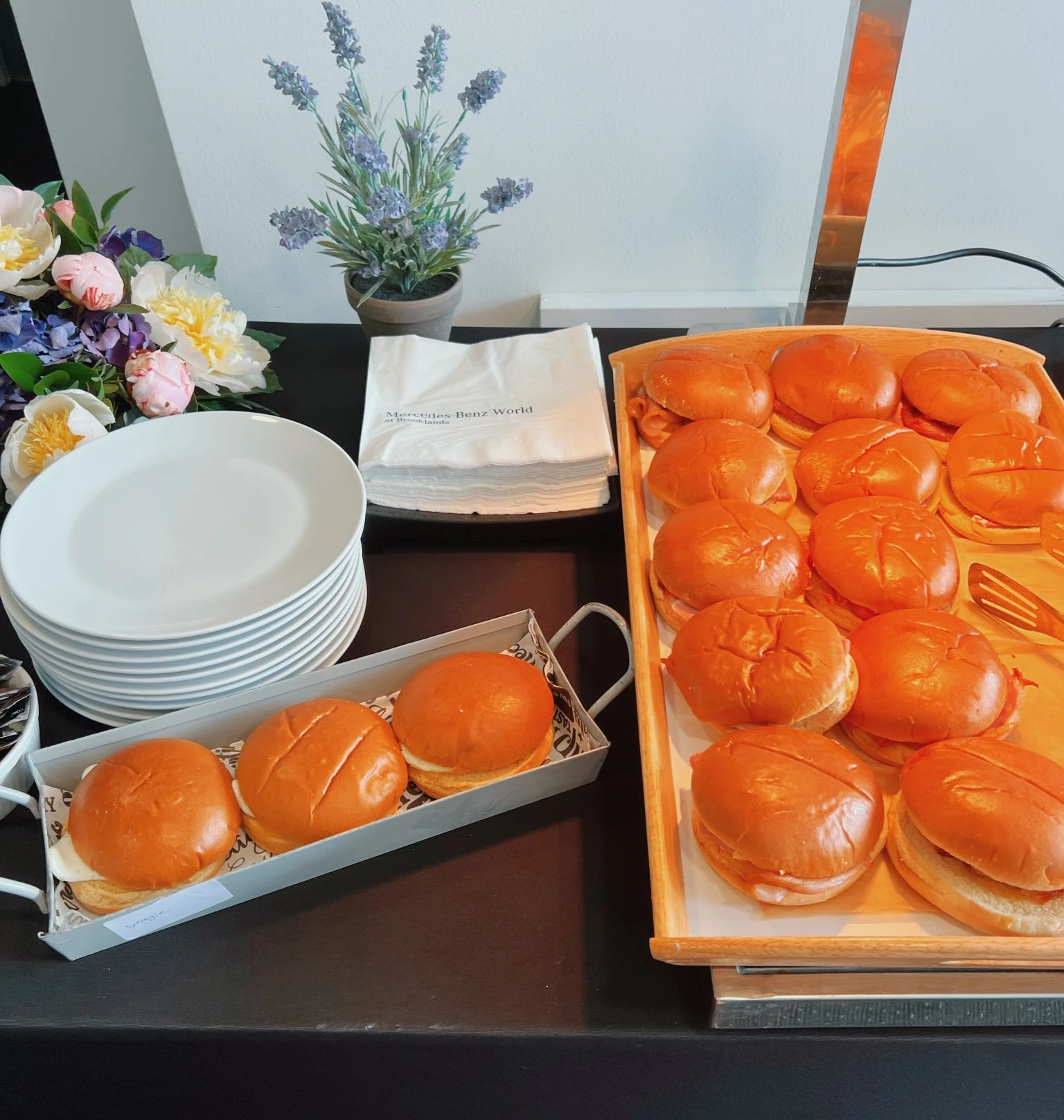 Tray of filled brioche rolls beside plates, flowers and Mercedes-Benz World napkins