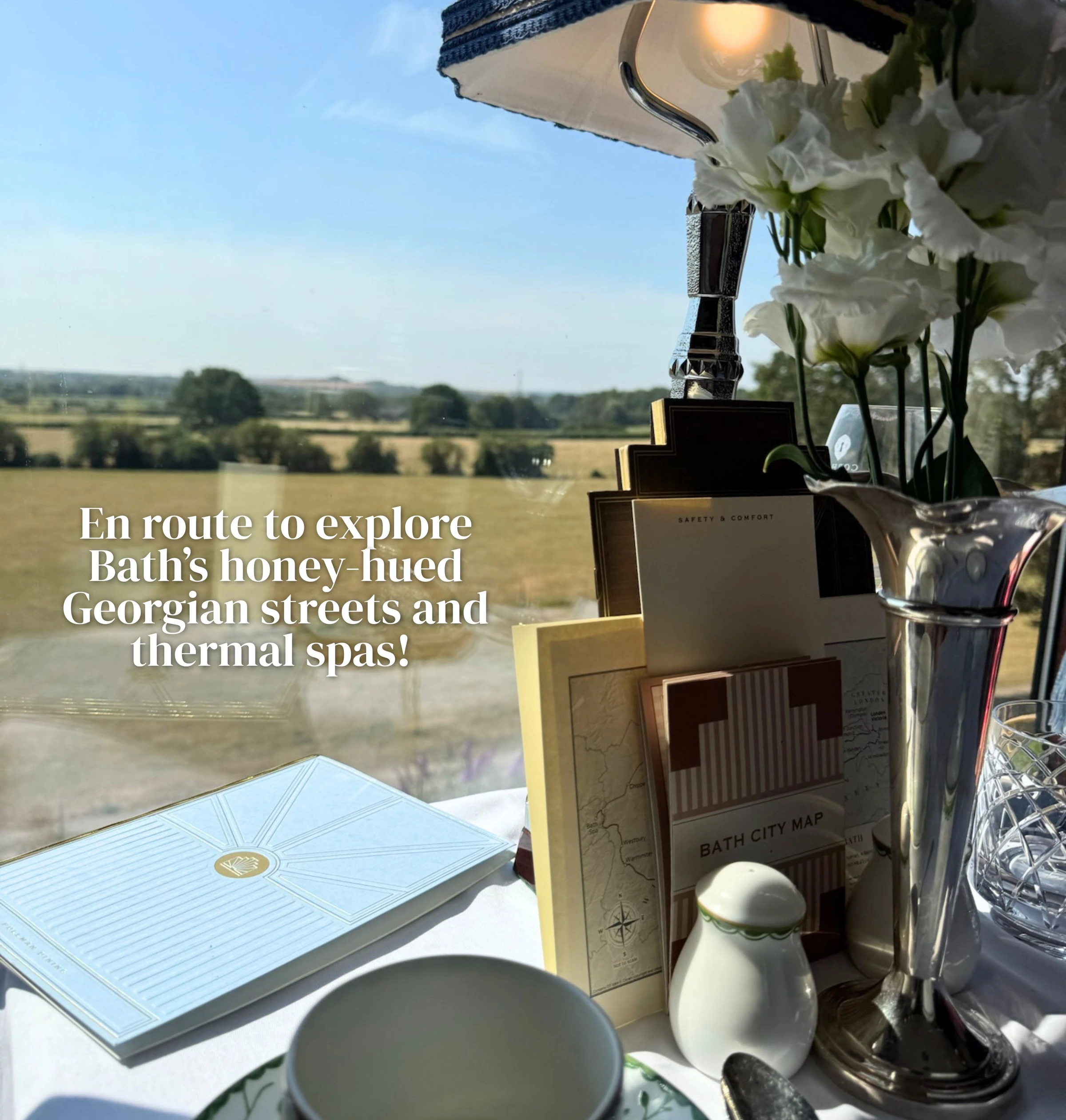 Elegant train table setting with flowers, silver lamp and Bath City Map overlooking the countryside