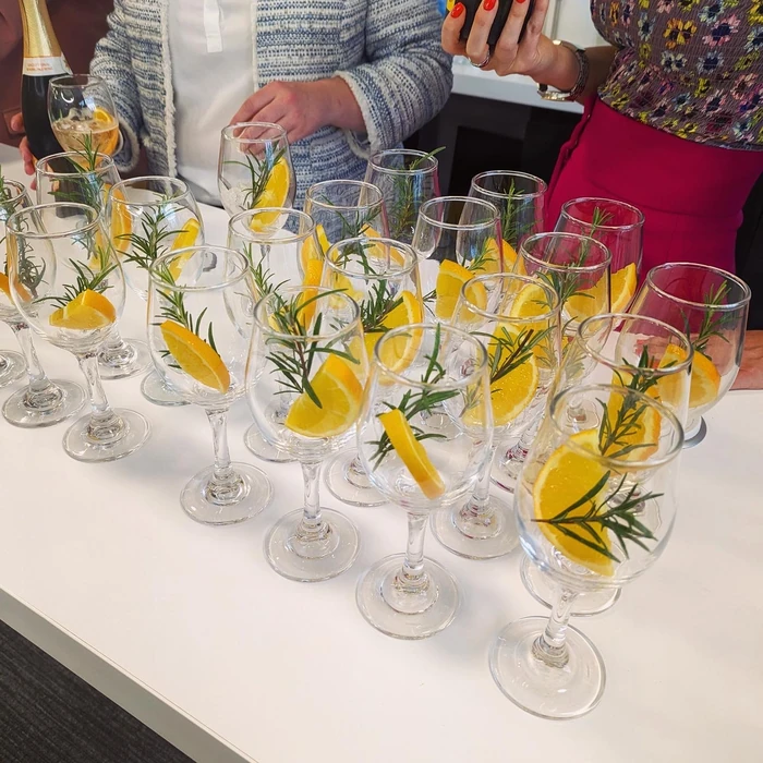 Glasses of wine garnished with orange slices and rosemary at an independent winemakers' tasting event