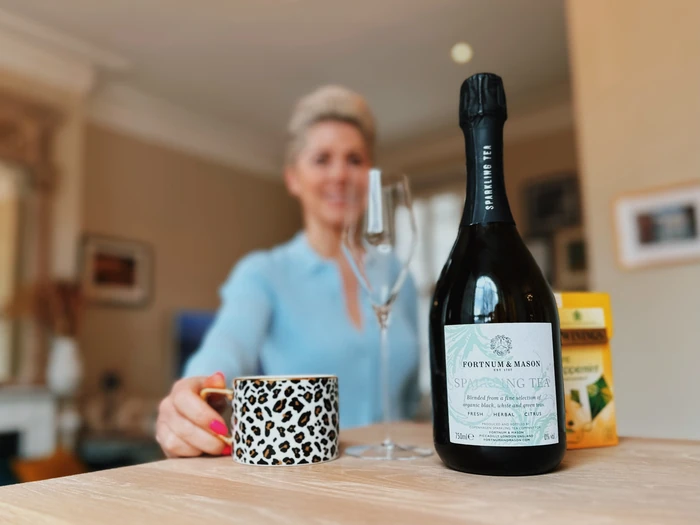 Sparkling tea bottle, wine glass and leopard print mug on table