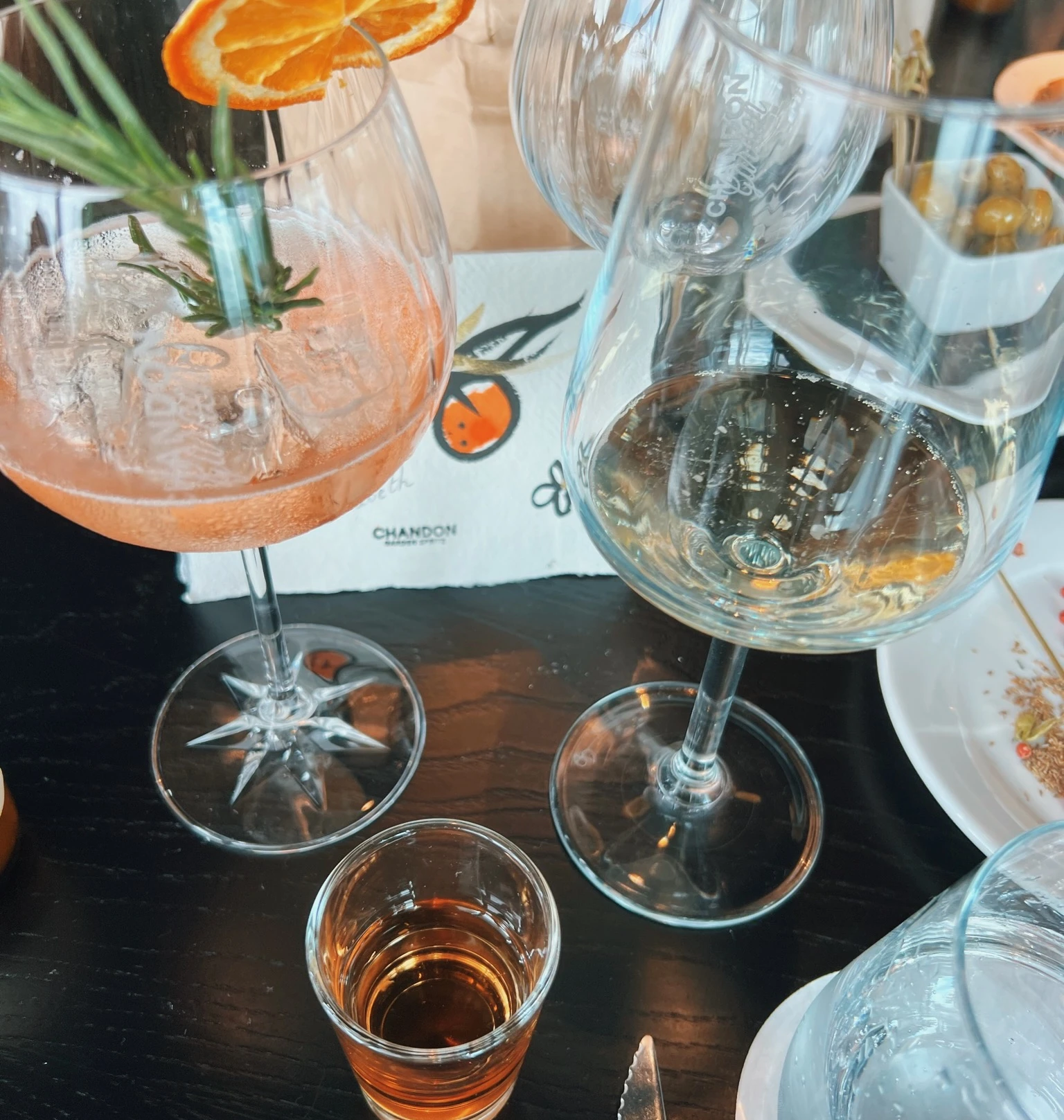 Chandon glasses and a pink sparkling drink garnished with orange and rosemary on a tasting table