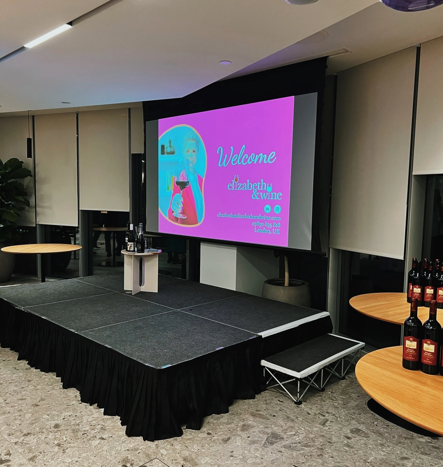 Wine tasting stage with Elizabeth & Wine welcome screen and bottles arranged on tables