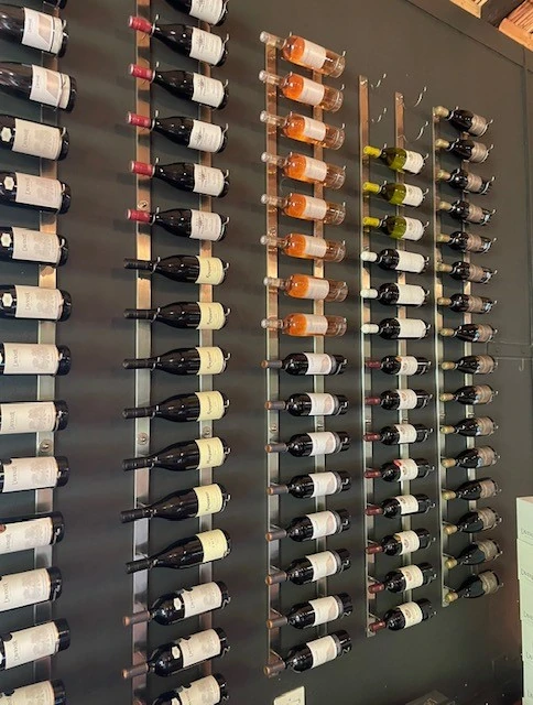 Wall-mounted wine bottles displayed on dark shelving in rows