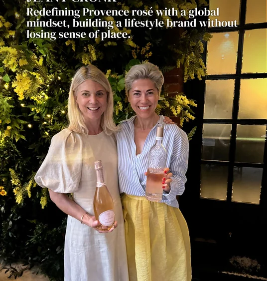 Two women hold bottles of Mirabeau rosé in front of a floral display