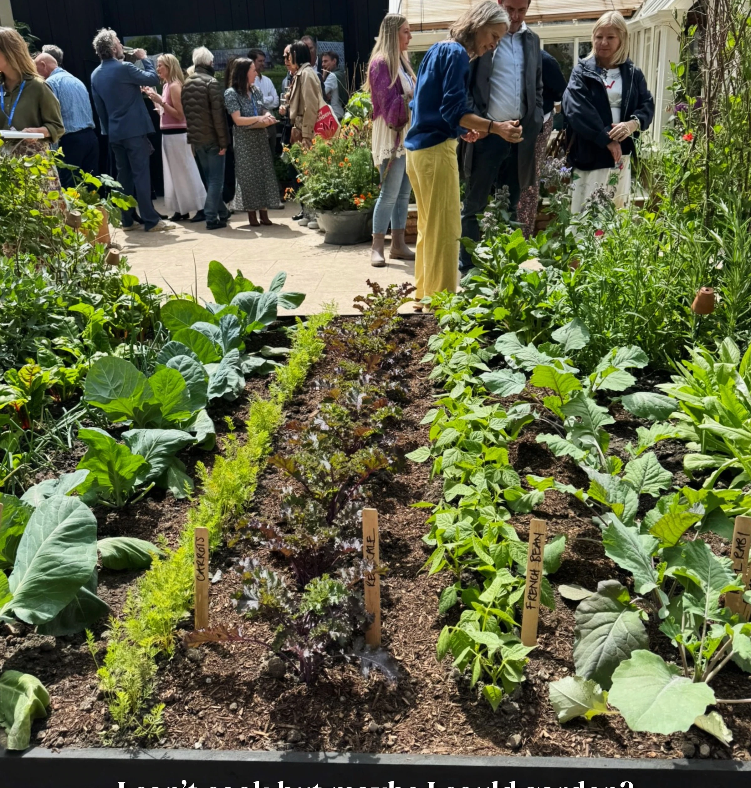 Visitors gather beside a vegetable garden display at the Chelsea Flower Show