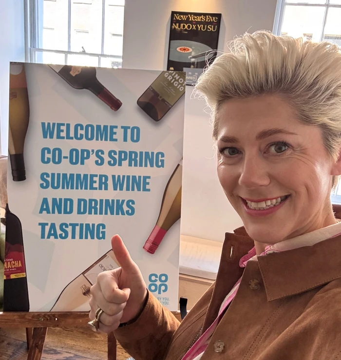 Woman beside Co-op spring summer wine tasting poster