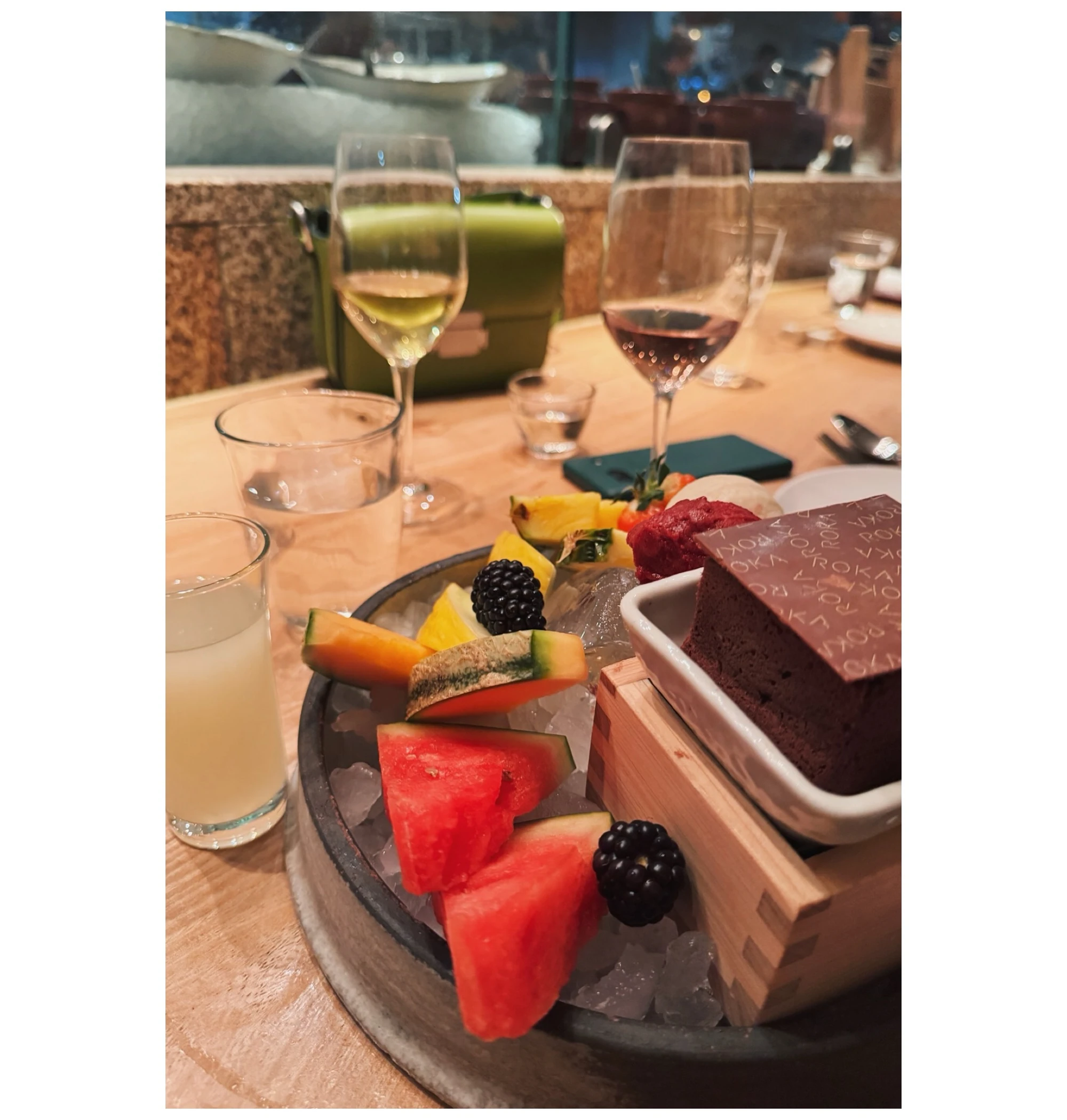Wine glasses and fruit platter with chocolate cake on a restaurant table