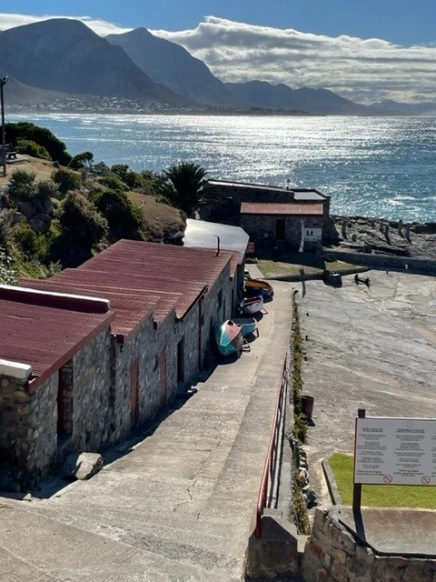 Coastal stone buildings beside sparkling sea and mountains