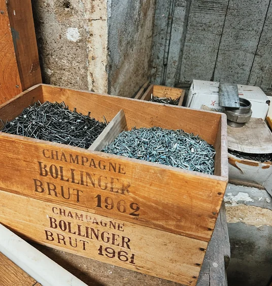 Wooden crates labelled Champagne Bollinger Brut 1962, filled with nails in a cellar workshop
