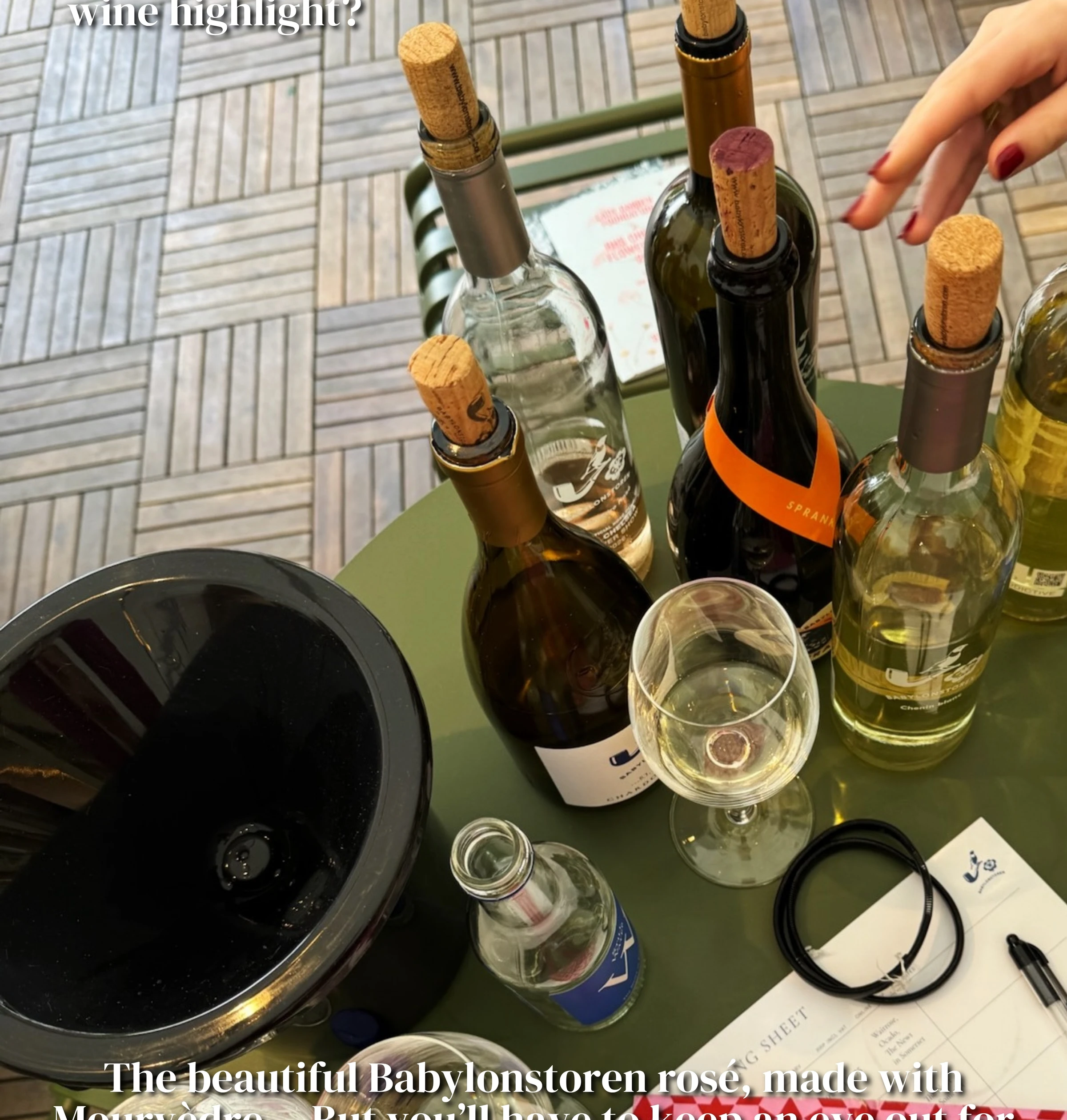 Wine bottles, a tasting glass and ice bucket on a green table at Chelsea Flower Show