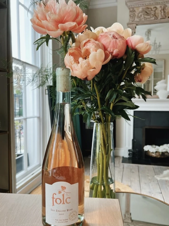 Bottle of dry English rosé beside peach flowers in vase