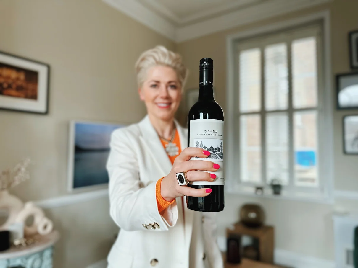 Woman holding a wine bottle indoors in a bright room