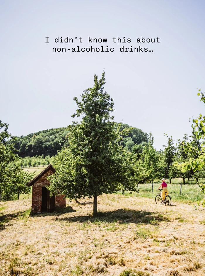Woman cycling in sunny orchard with small brick shed and trees
