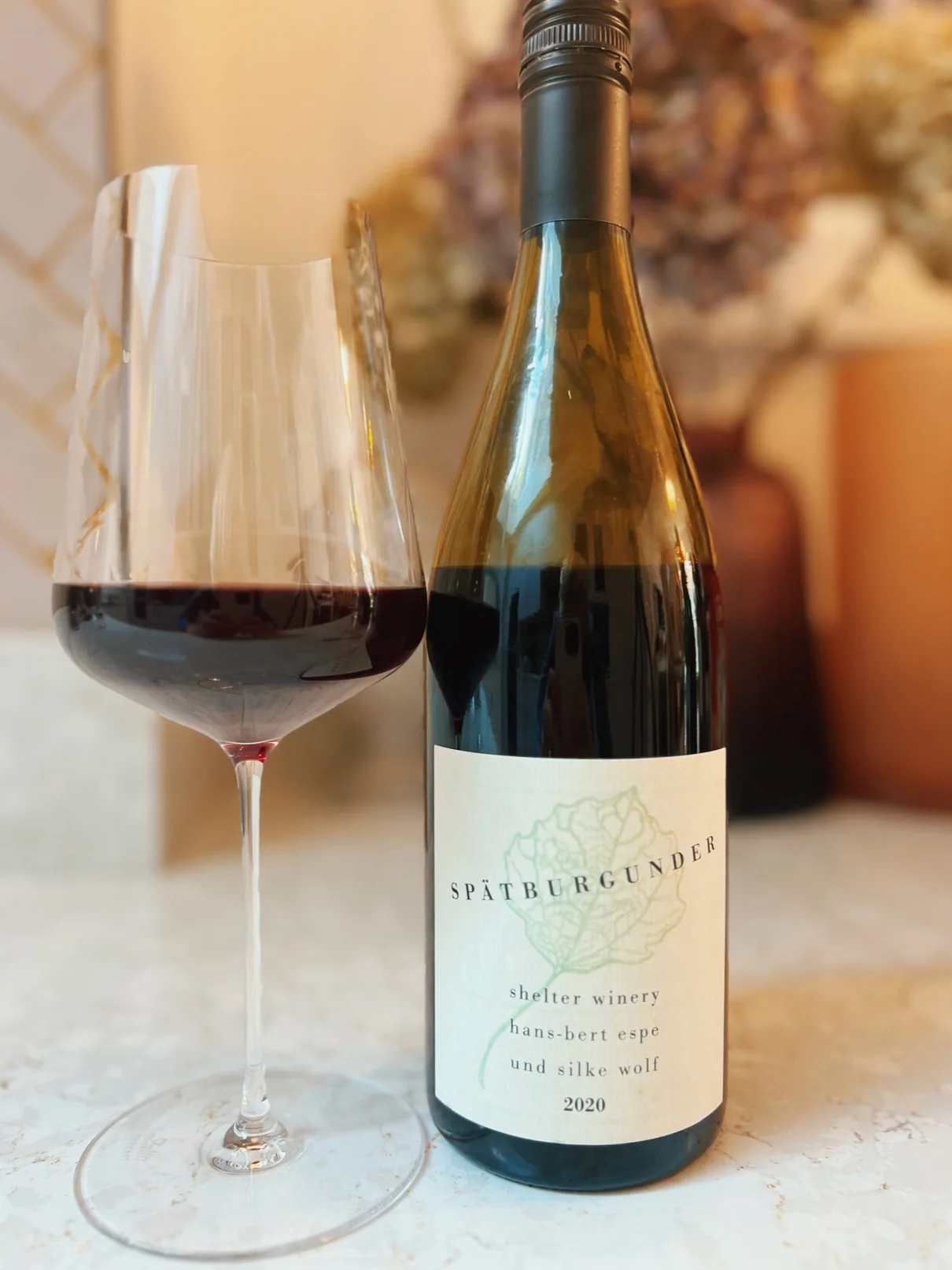 Glass of red wine beside Spätburgunder bottle on a table