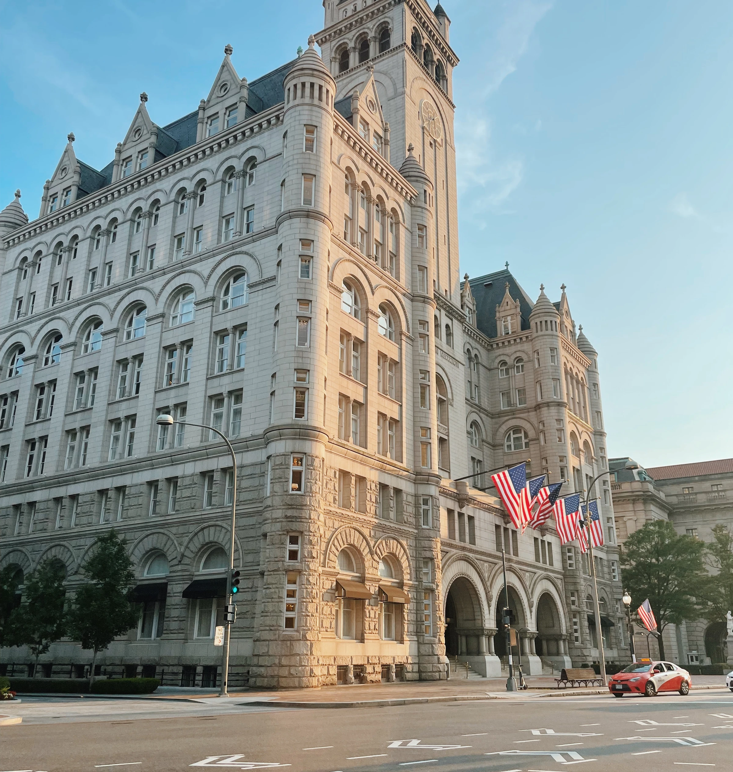 Grand historic stone building with American flags beside a city street