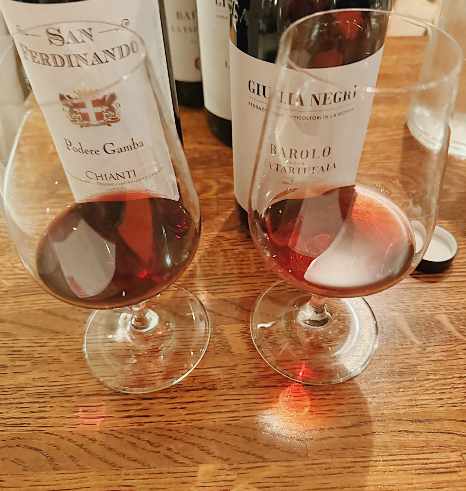 Italian wine bottles and partially filled wine glasses on a wooden table