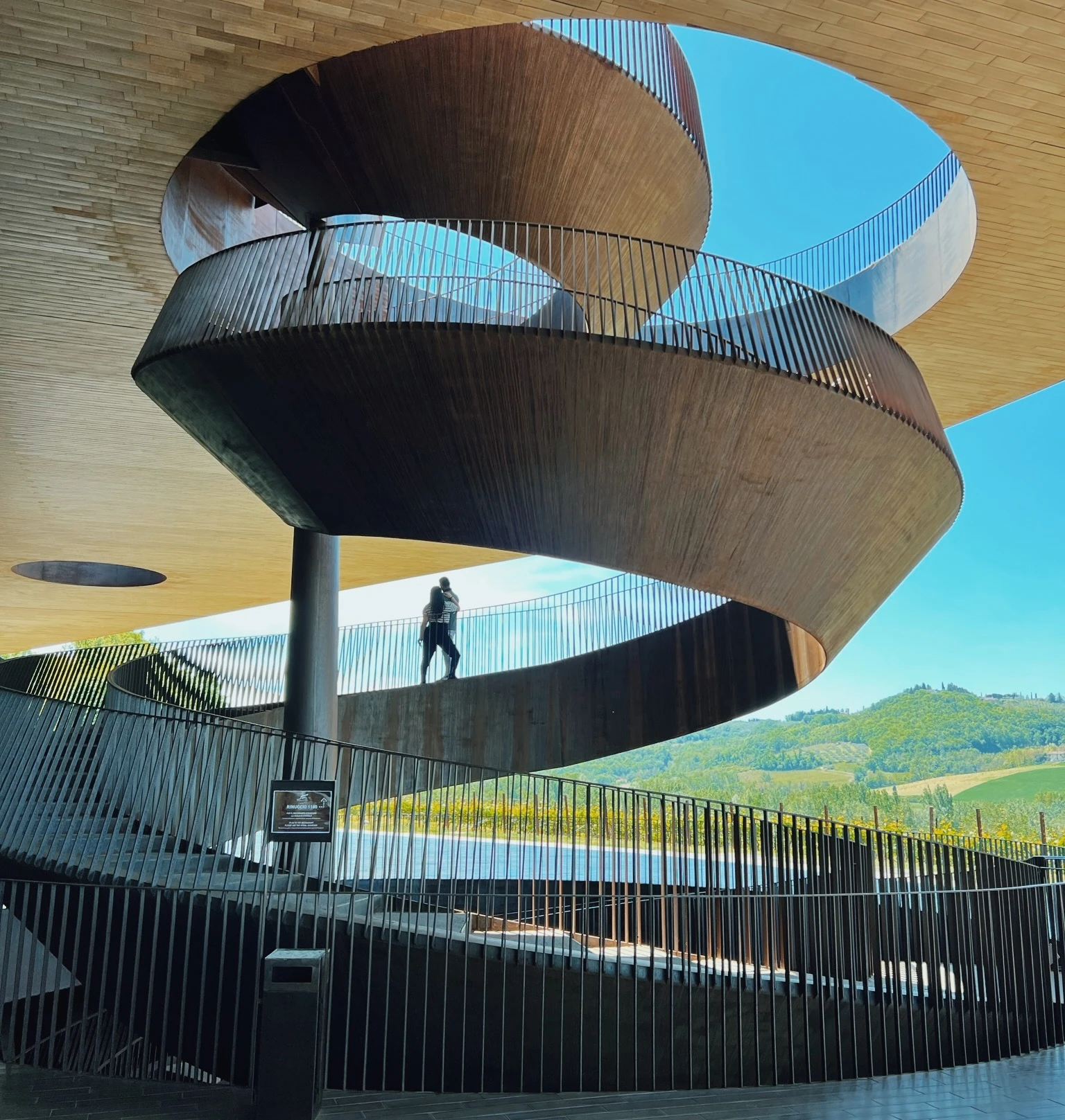 Sculptural spiral staircase inside the Antinori winery, with Tuscan hills visible through the open walls.
