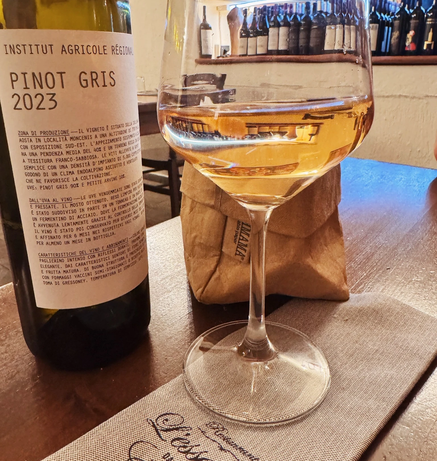 Bottle of Pinot Gris 2023 and a glass of white wine on a restaurant table in Champoluc