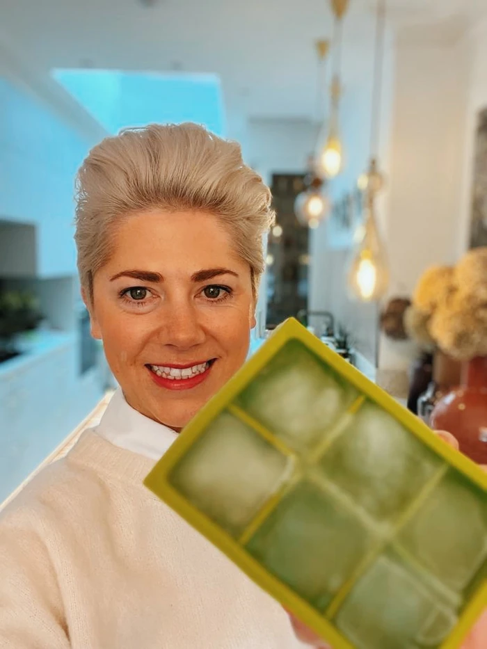 Smiling woman holding green wine tasting card indoors