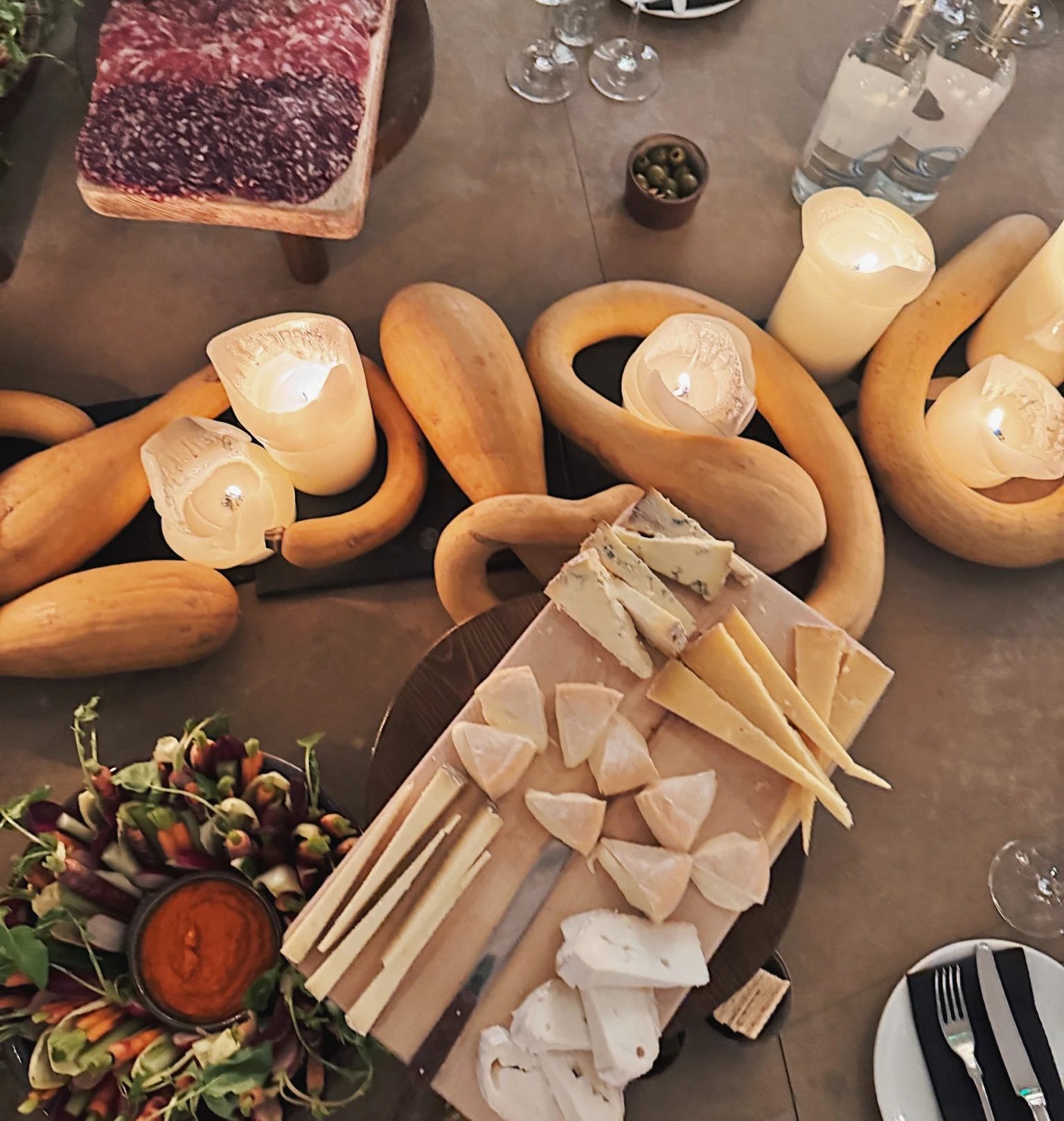 Cheese, charcuterie and vegetables arranged on a candlelit tasting table