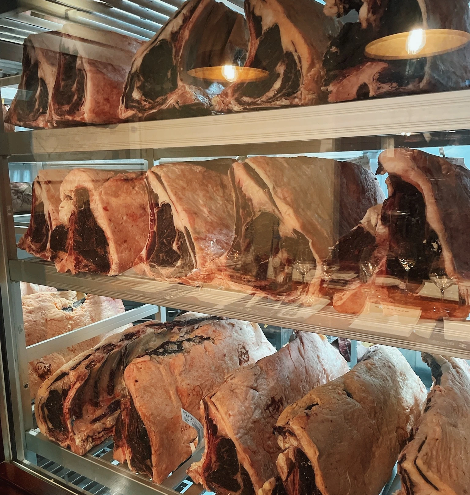 Large cuts of meat displayed on shelves in a chilled counter