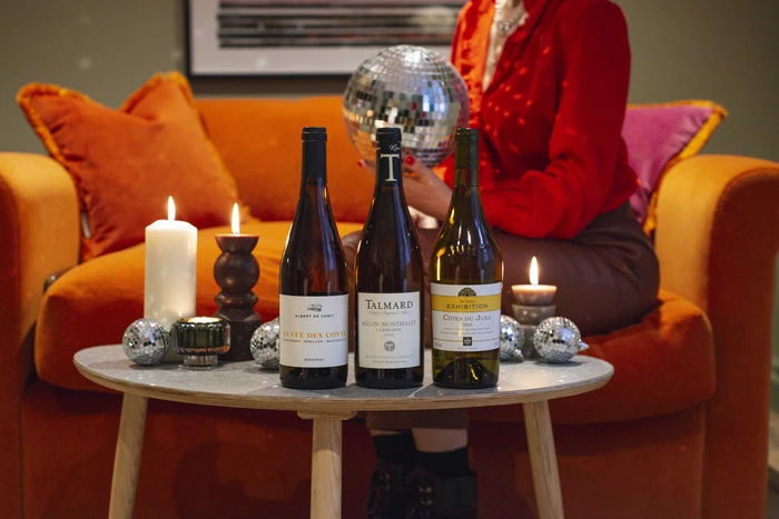 Three wine bottles with candles and disco balls on table