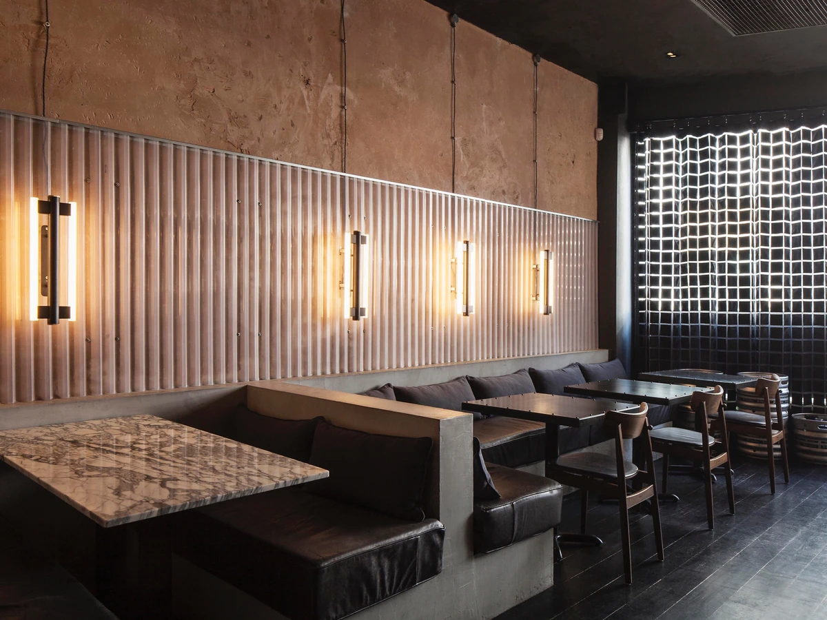Modern restaurant interior with booths, tables, chairs, marble tabletop and illuminated wall feature