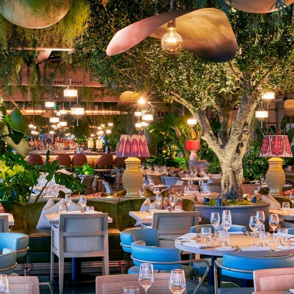Elegant restaurant interior with plants, hanging lights, dining tables and wine glasses