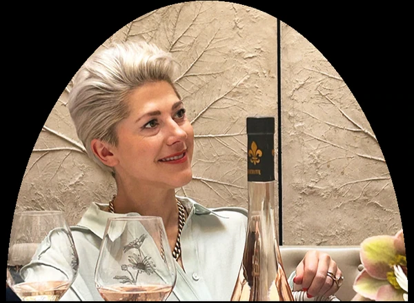 Short-haired woman beside wine glasses and a bottle at a table