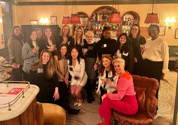 Group of women posing with wine glasses in a warmly lit bar