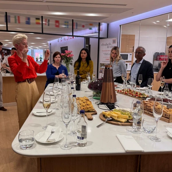 People gathered around a wine tasting table with glasses, bottles, cheese and food
