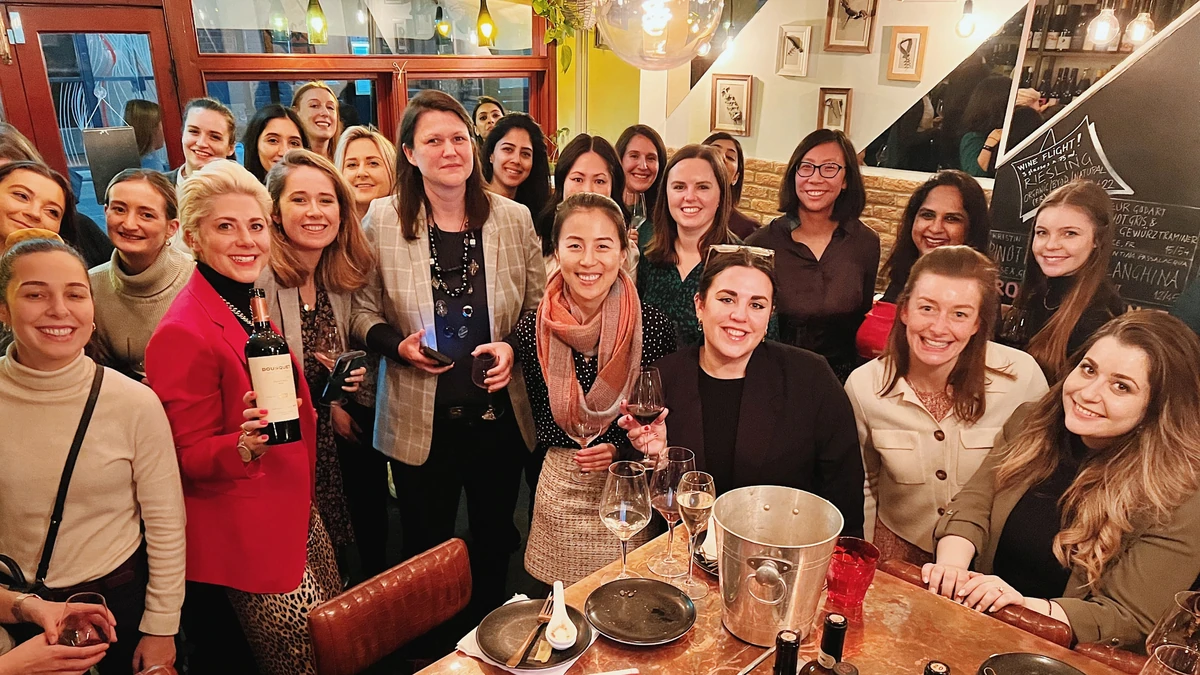 Group of women smiling at a wine event around a table with bottles and glasses