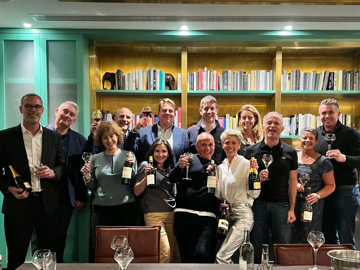 Group posing with wine bottles and glasses in front of a bookcase