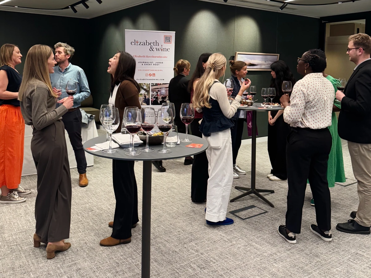 People mingling around tables of wine glasses at an indoor tasting event