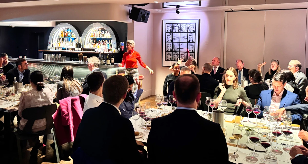 People seated at tables tasting wine while a woman speaks in a restaurant event space