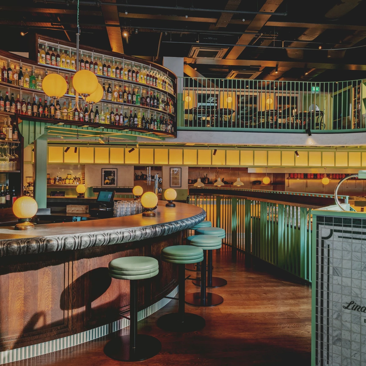 Interior of a stylish bar with curved counter, stools, bottles and mezzanine seating