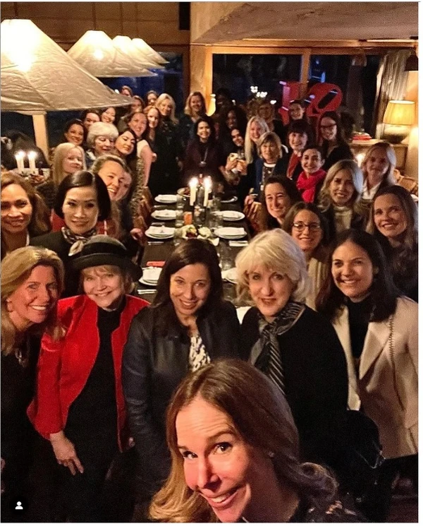 Large group of women posing around a candlelit dining table in a restaurant