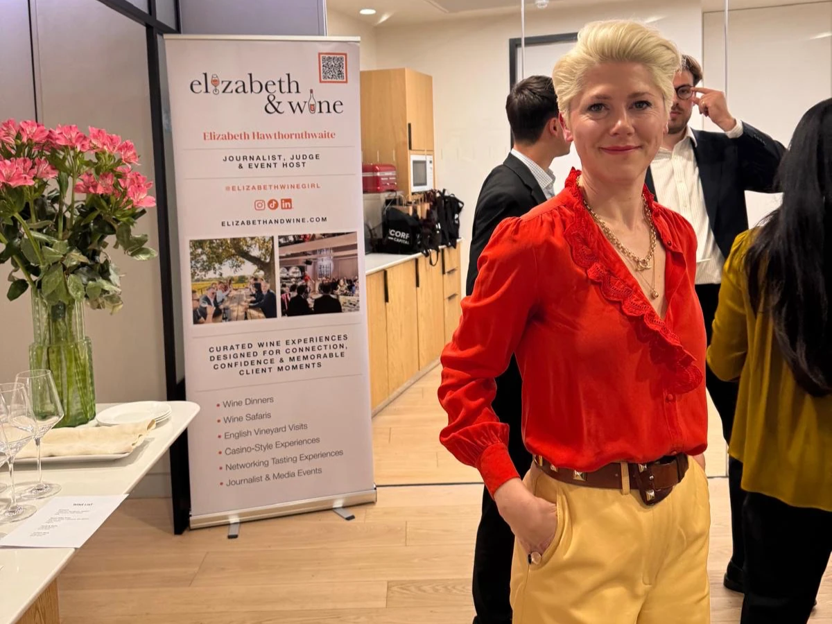 Woman in red blouse beside Elizabeth & Wine event banner
