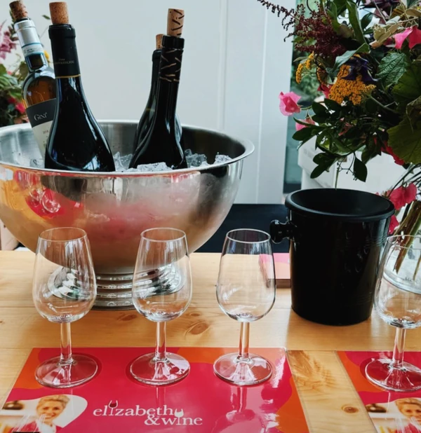 Wine bottles in an ice bucket, empty glasses, flowers and Elizabeth & Wine brochures