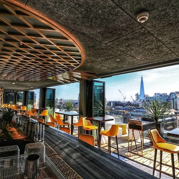 Rooftop bar with orange chairs and views of The Shard in London