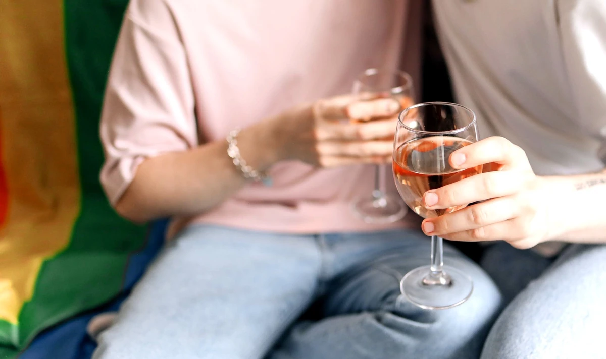 Two people holding glasses of rosé wine while seated beside each other