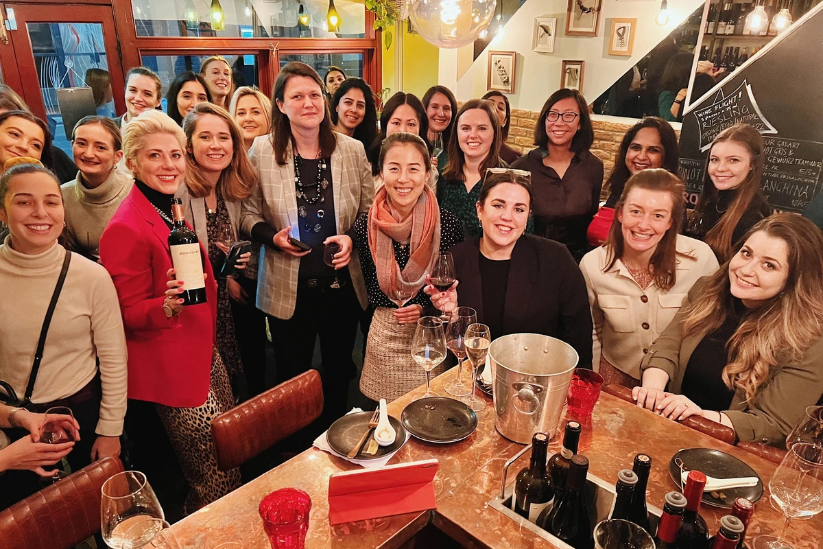 Group of women gathered around a restaurant table with wine bottles and glasses