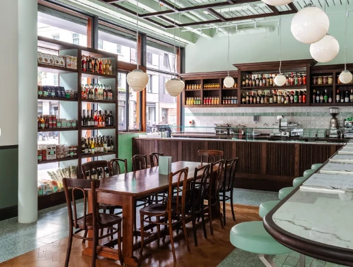 Bright wine bar interior with bottles, wooden tables, stools and hanging globe lights