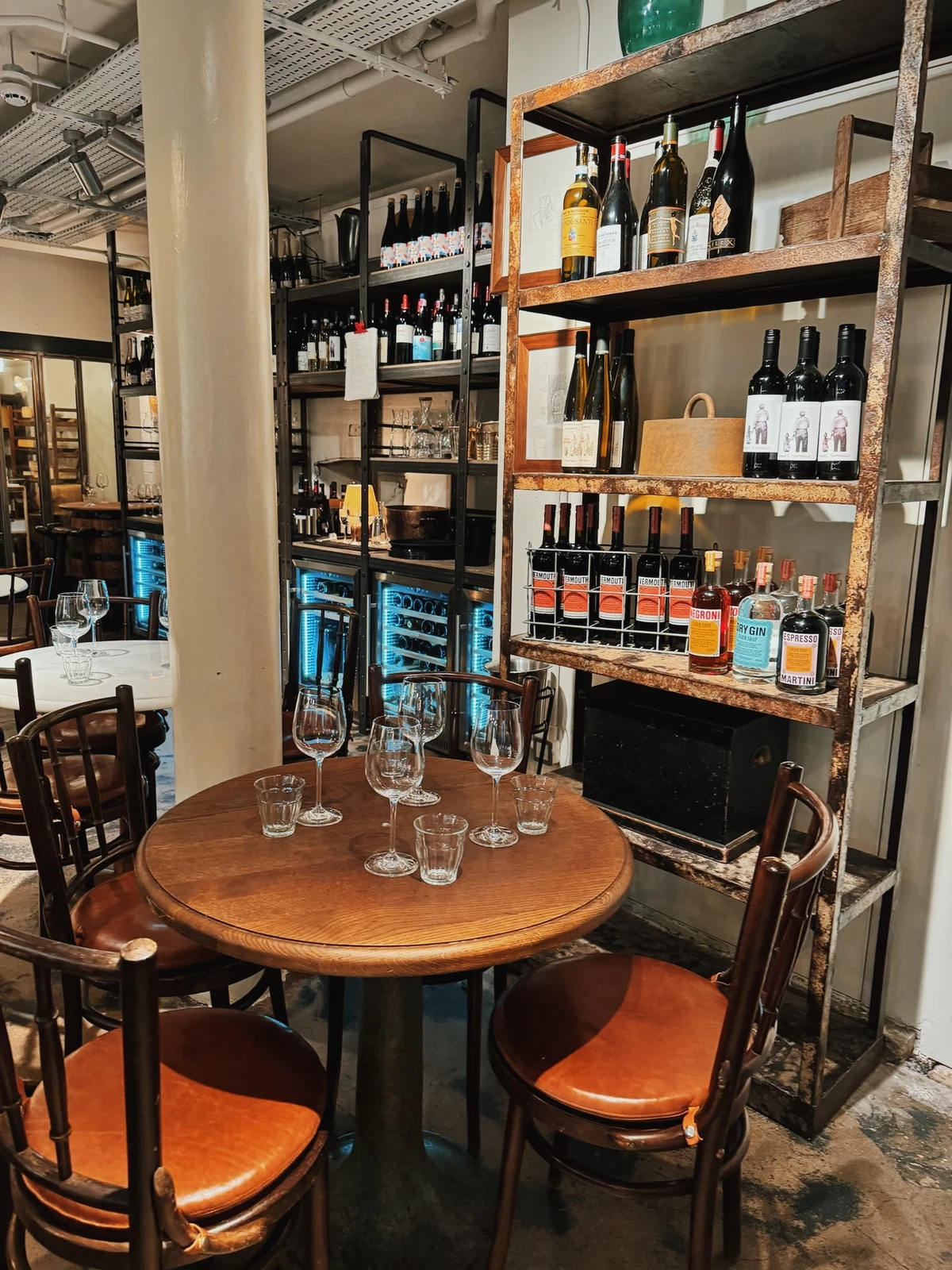 Wine bottles displayed on shelving beside a set table in a wine bar