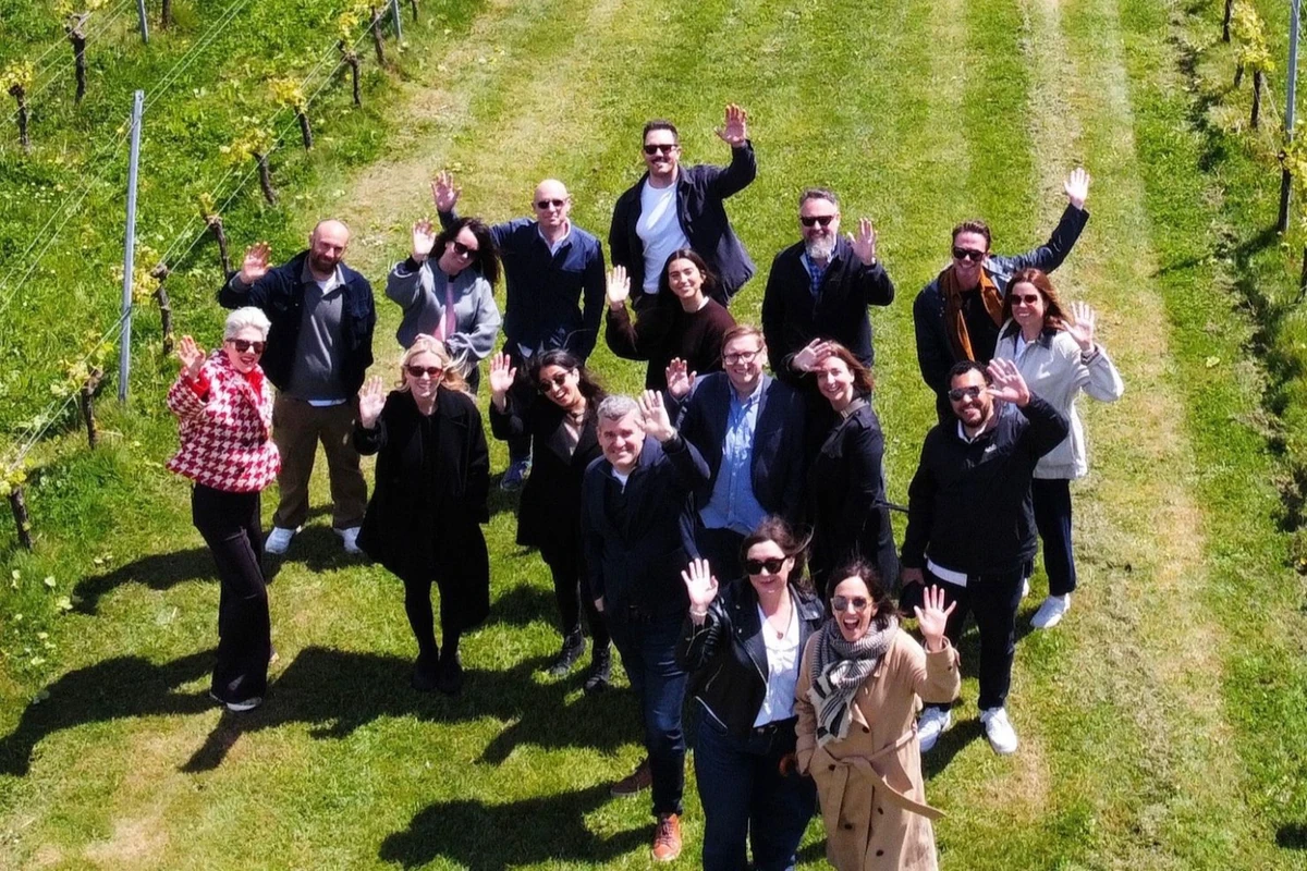 Group of people waving among vineyard rows