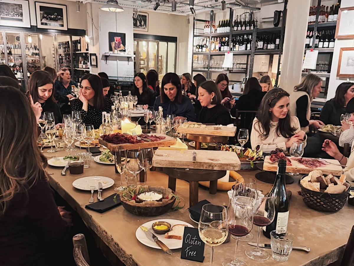People dining at a long table with wine glasses, charcuterie and cheese boards