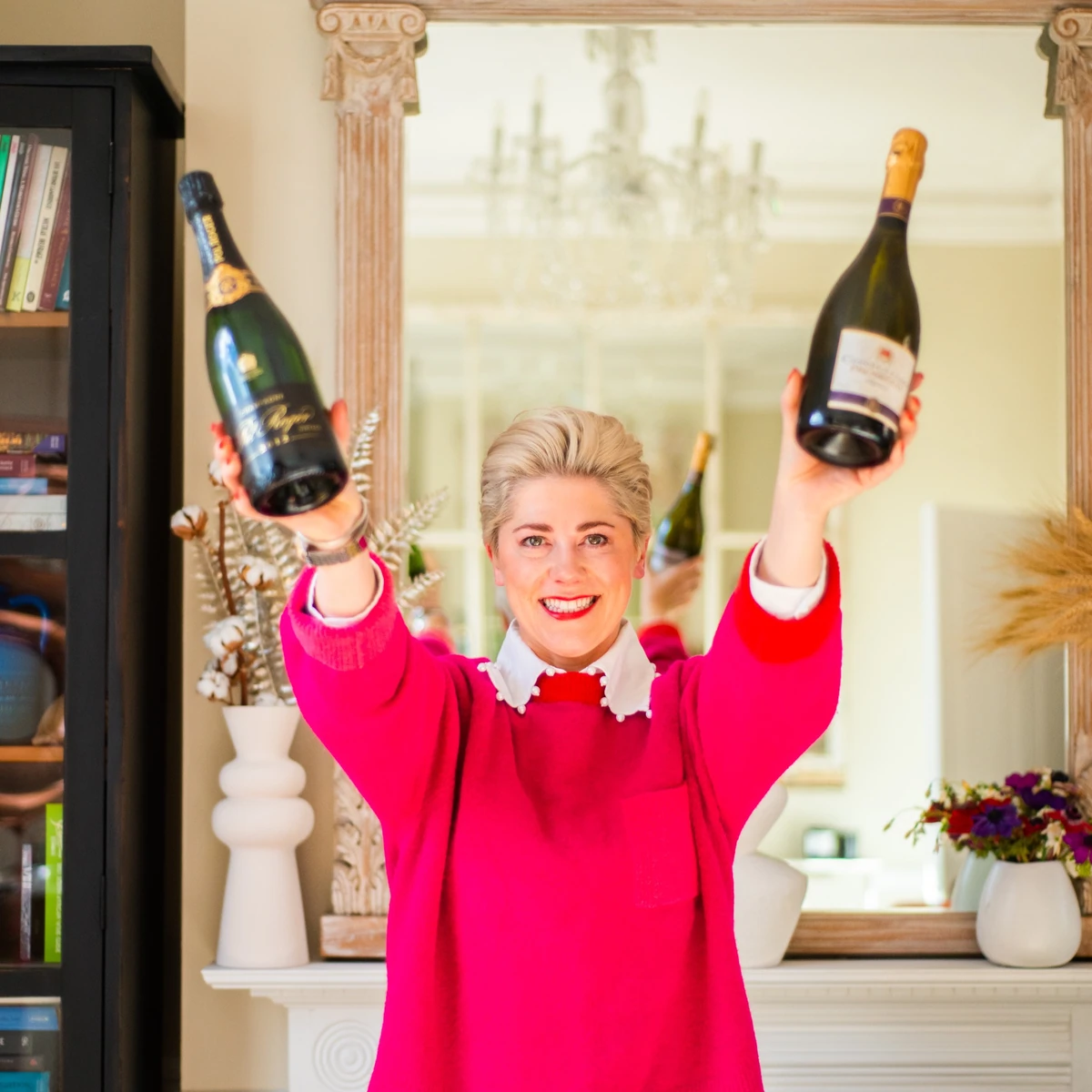 Woman holding two champagne bottles indoors