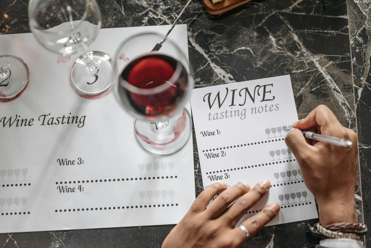 Wine tasting sheets, numbered glasses and red wine on a marble table