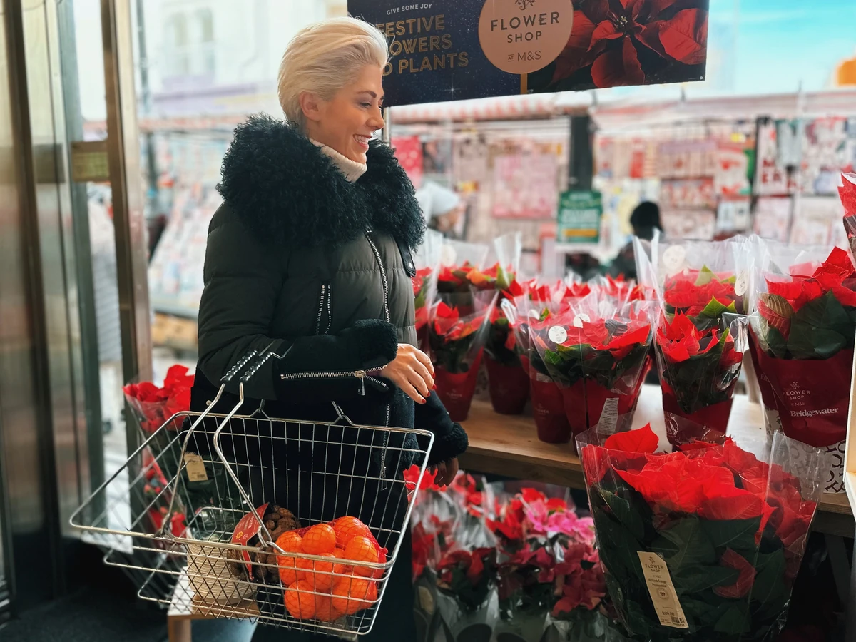 Woman with shopping trolley browsing red poinsettias in a flower shop